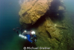 Side-mount diver examines one of the supporting rock pill... by Michael Grebler 